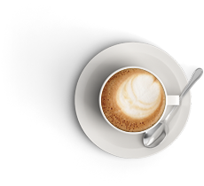 Aerial view of white coffee cup with foam showing in the cup on a white saucer with a silver spoon resting on the saucer.